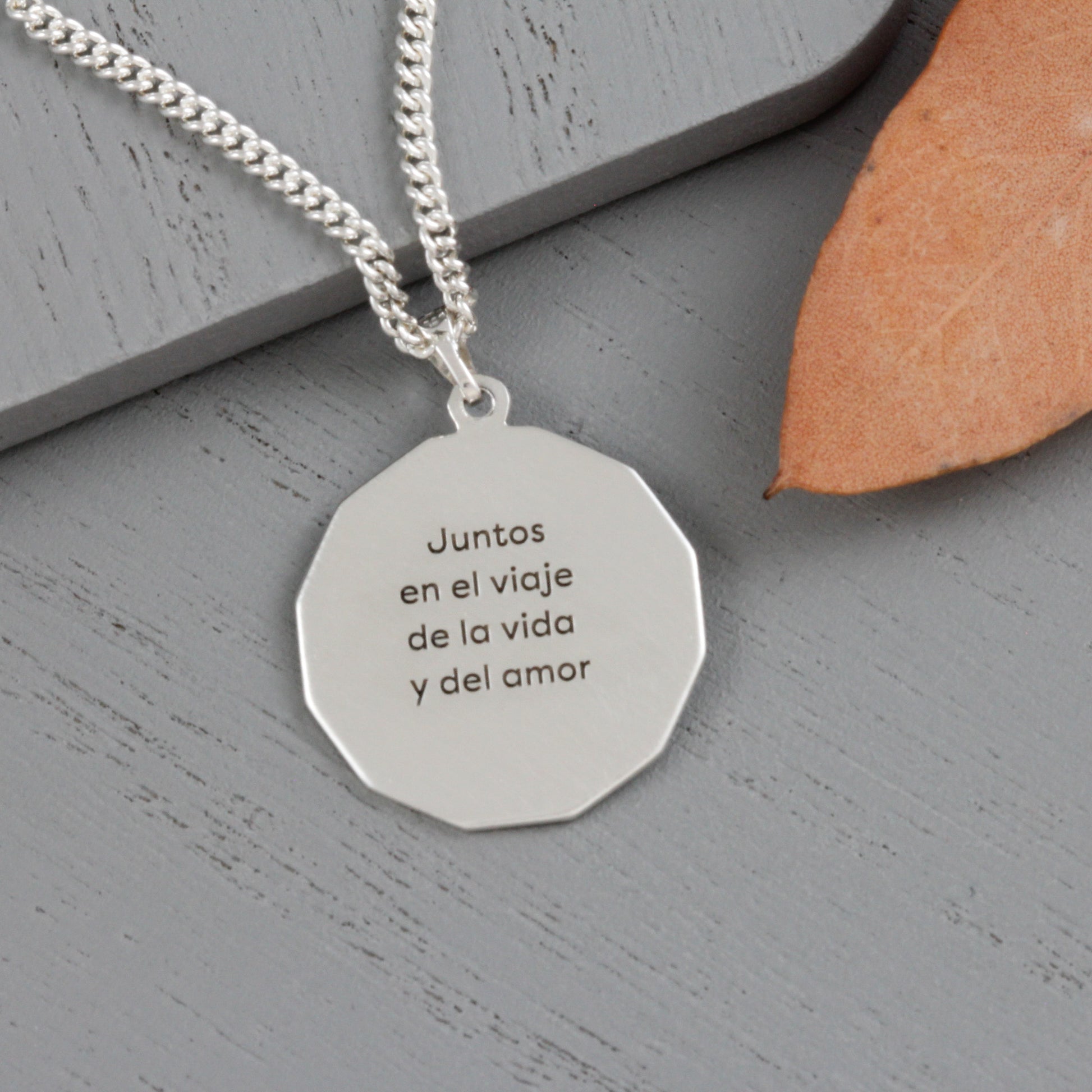 Close-up of a St. Christopher dodecagon pendant with a personalized message engraved on the back.