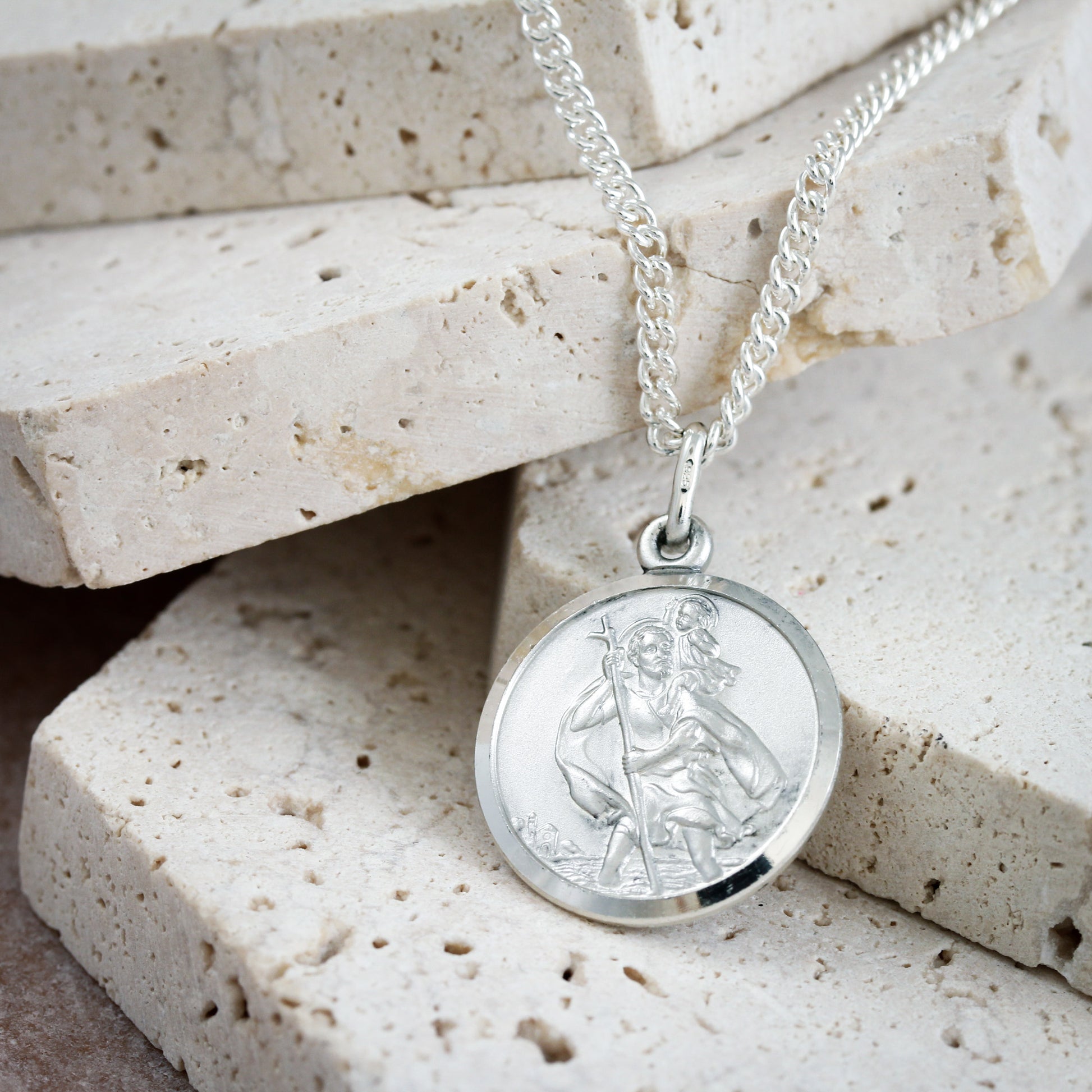 Silver St Christopher round pendant on a stone surface