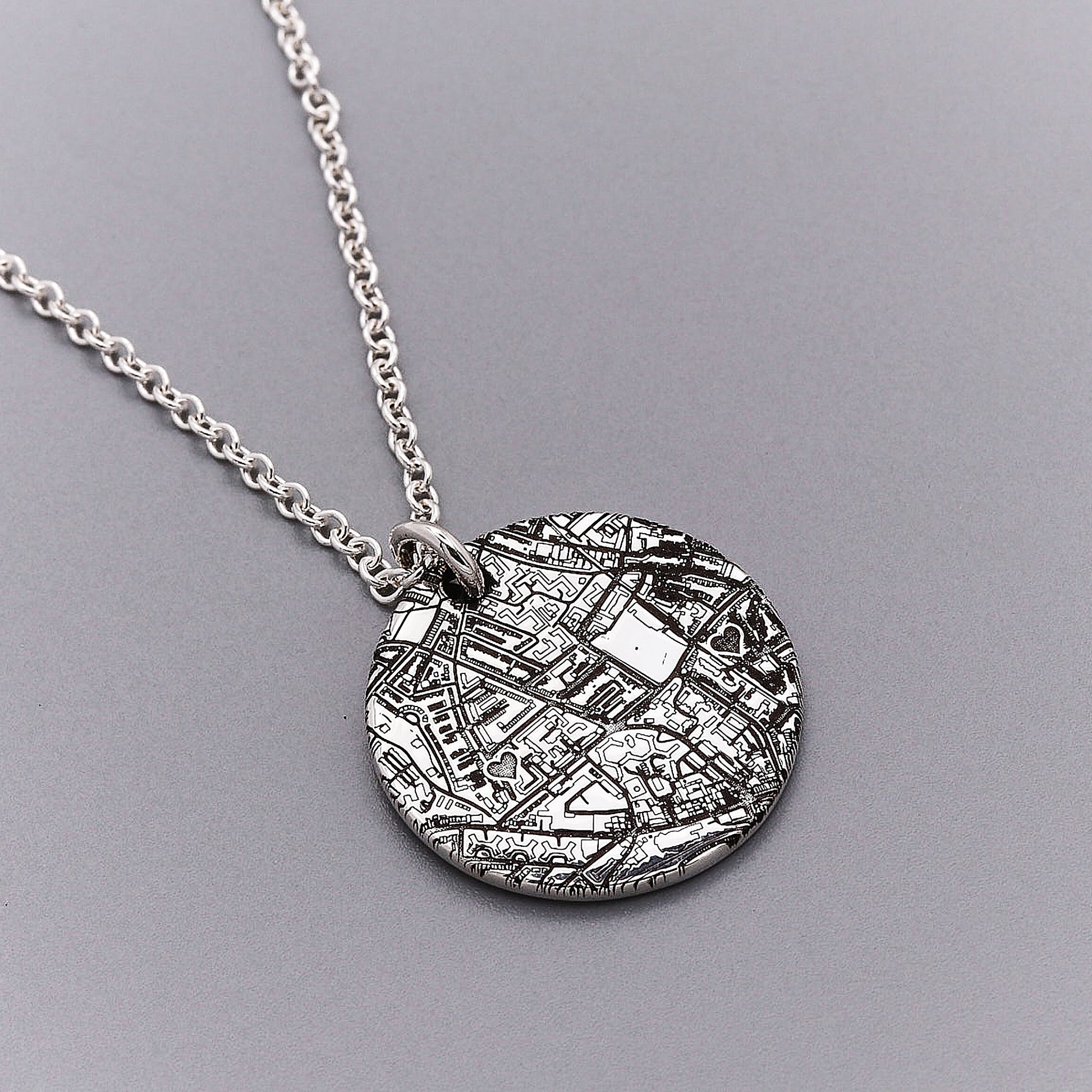 Silver necklace with a round map engraved pendant on a gray background