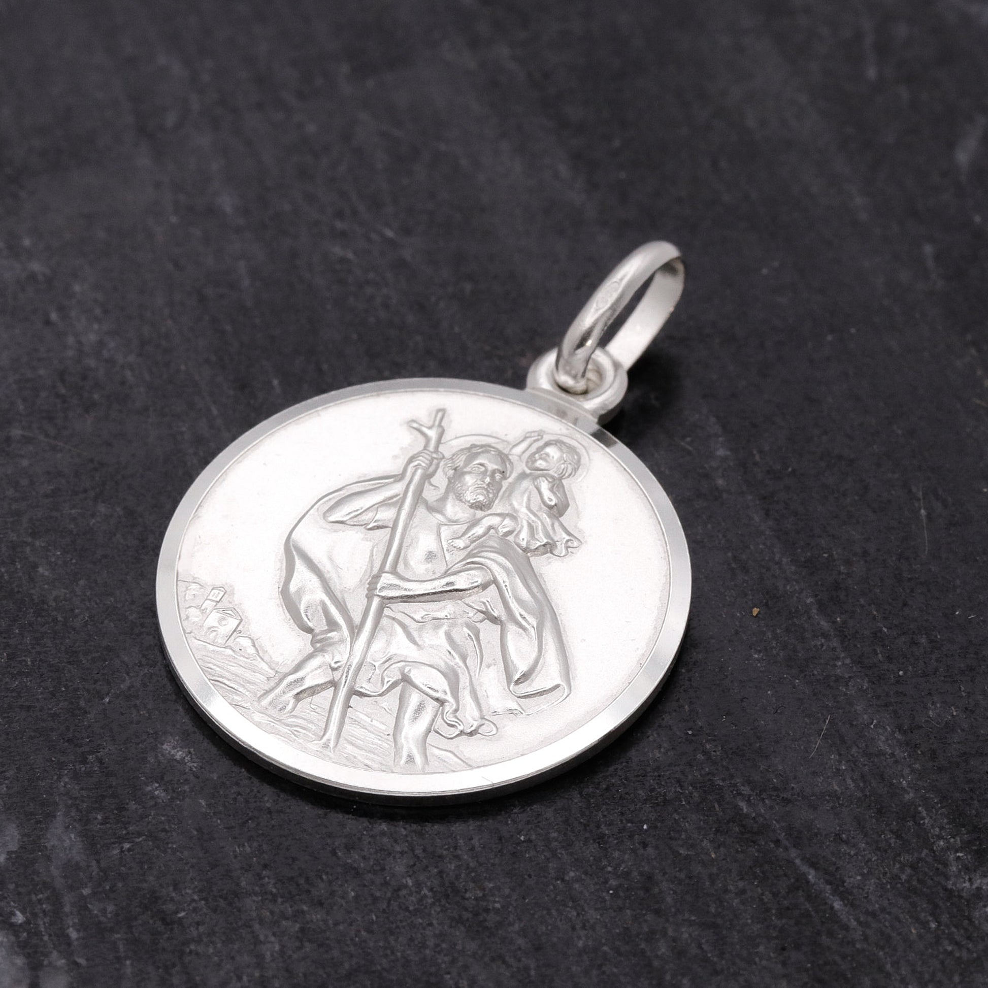 Silver pendant with religious design on a dark stone background