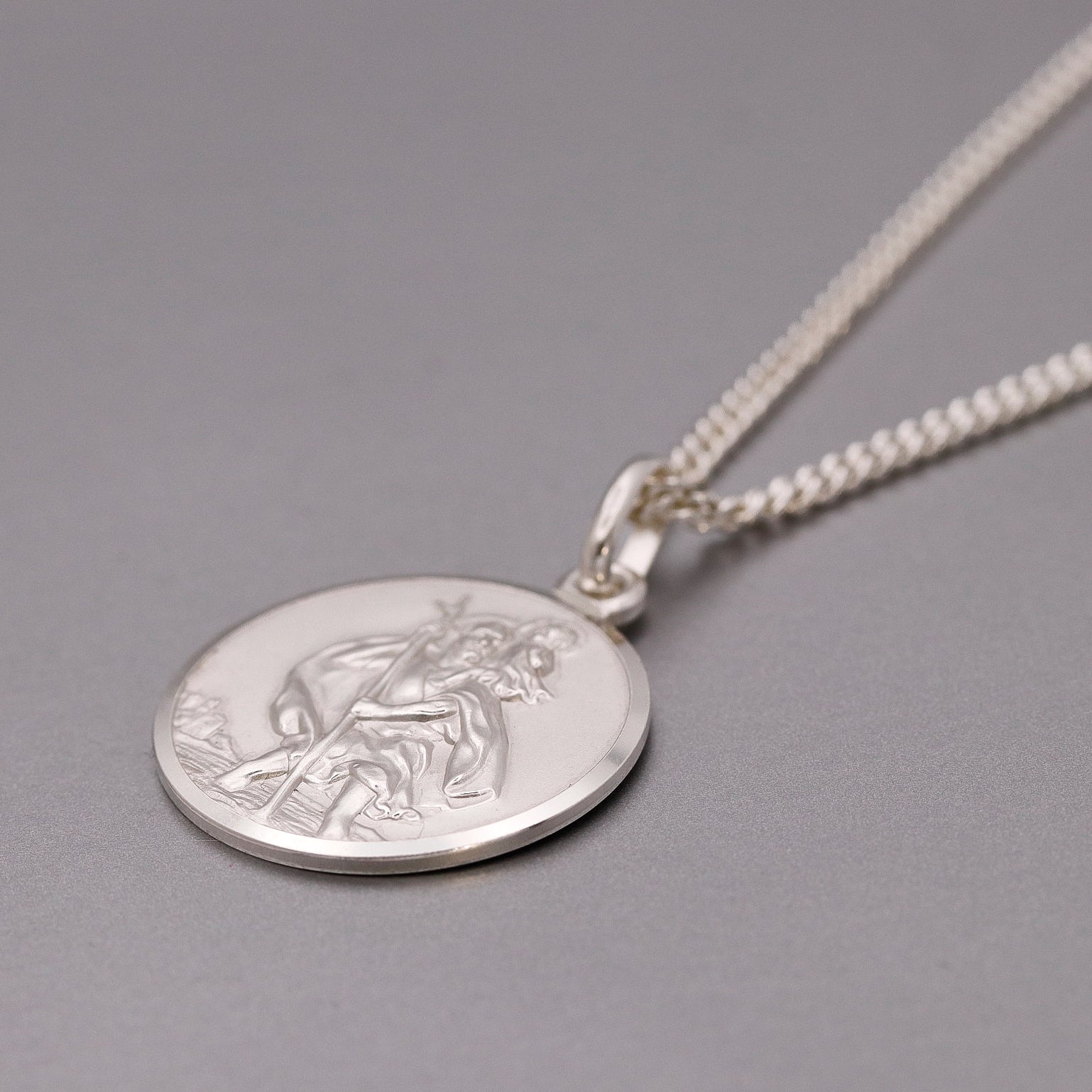 Silver St Christopher pendant necklace on a gray background