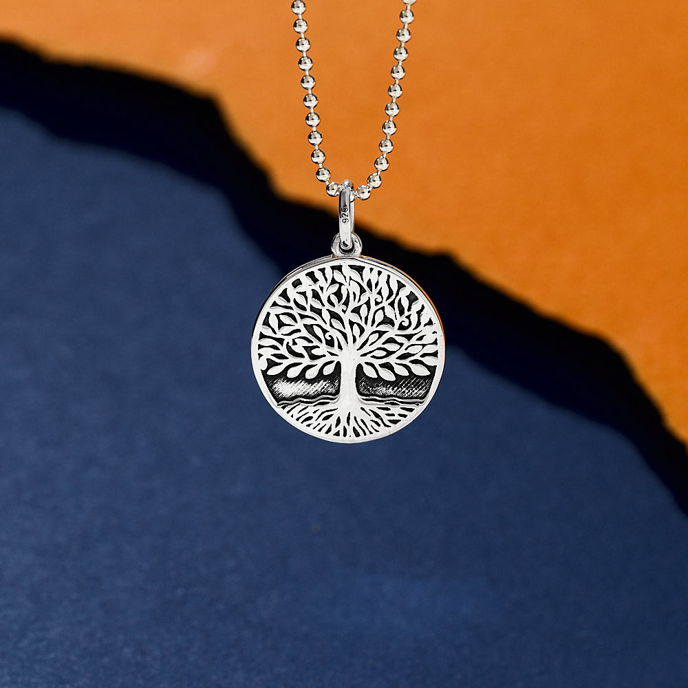 Silver tree of life 'Arbor Vitae' pendant on a chain against a blue background