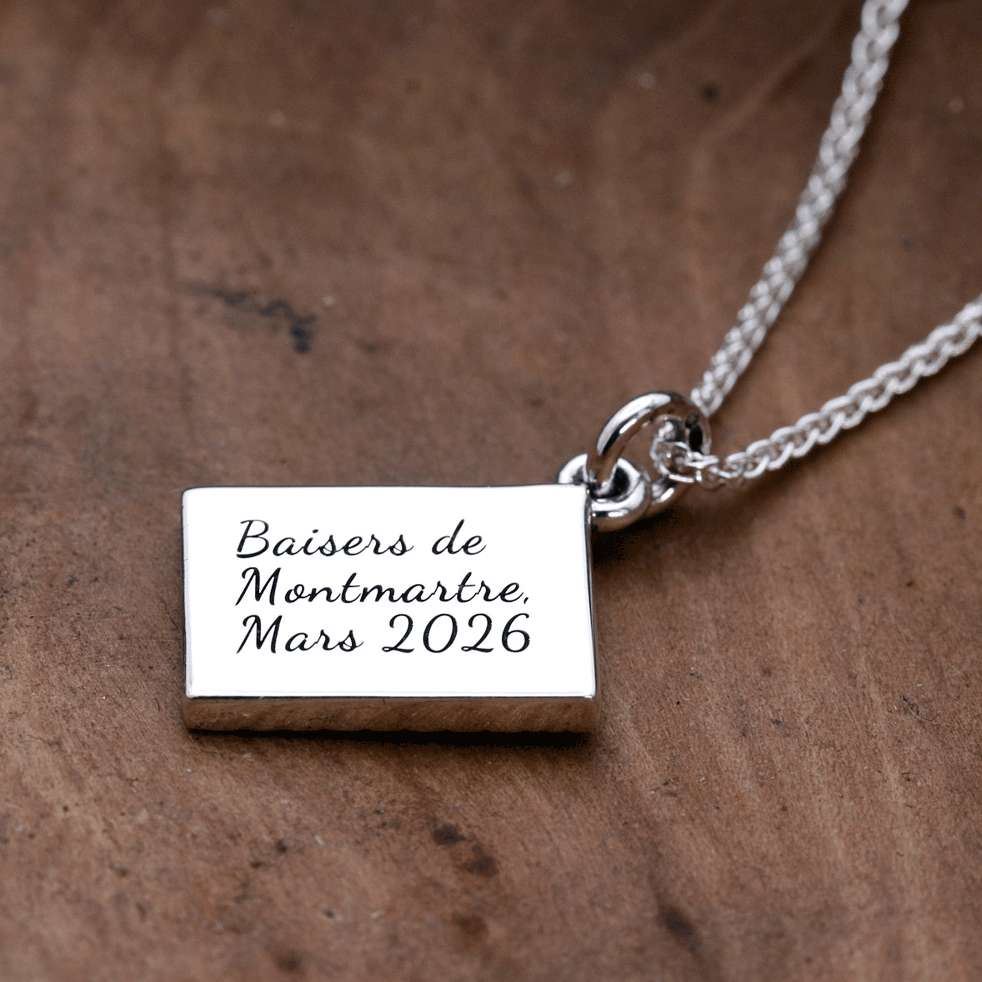 Silver necklace with a postcard pendant on a wooden surface