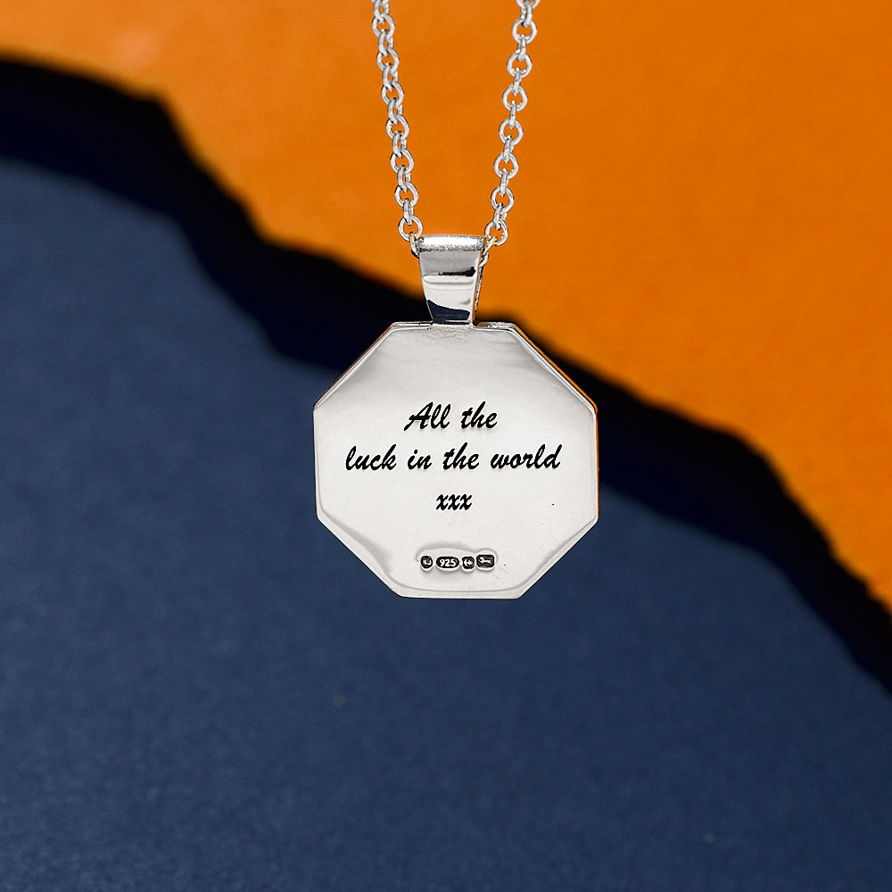 Silver necklace with an engraved lucky message pendant on a two-tone background