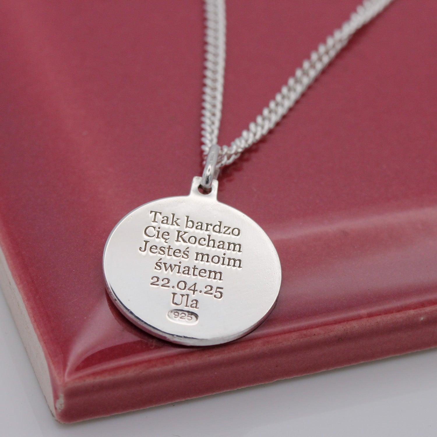 Silver necklace with an engraved pendant on a red background