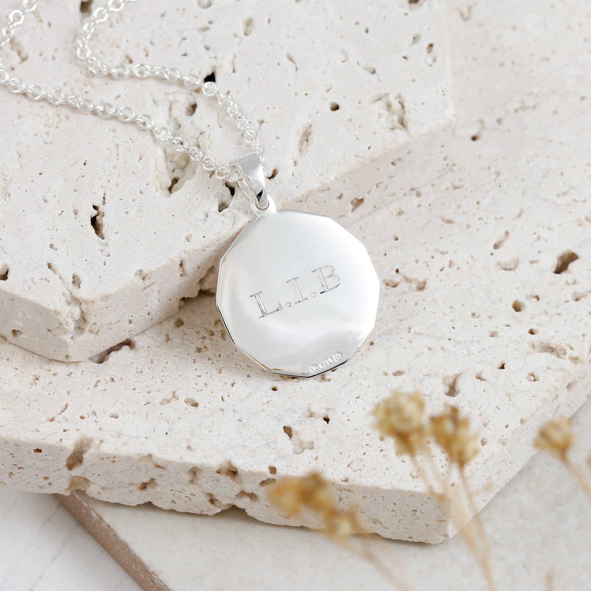 Silver necklace with a round pendant on a textured stone surface
