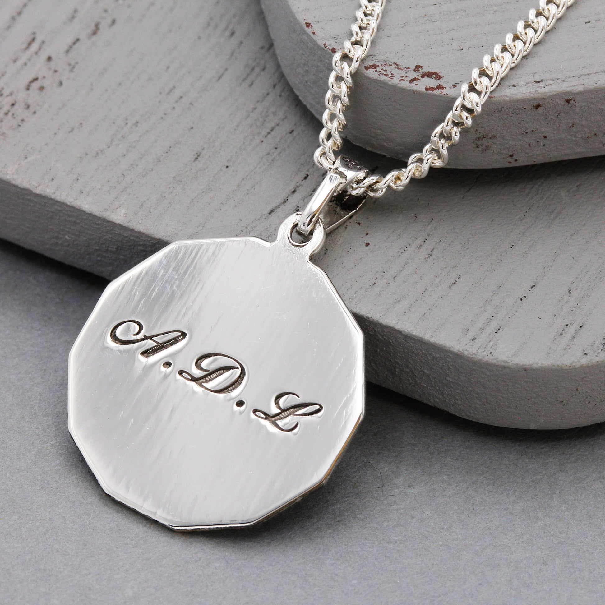 Silver necklace with a hexagonal pendant on a gray surface