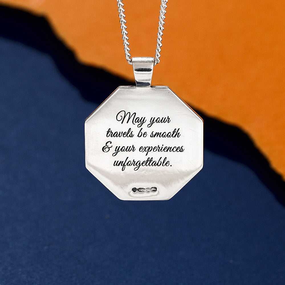 Silver octagon shaped necklace with engraved pendant on a blue and orange gradient background