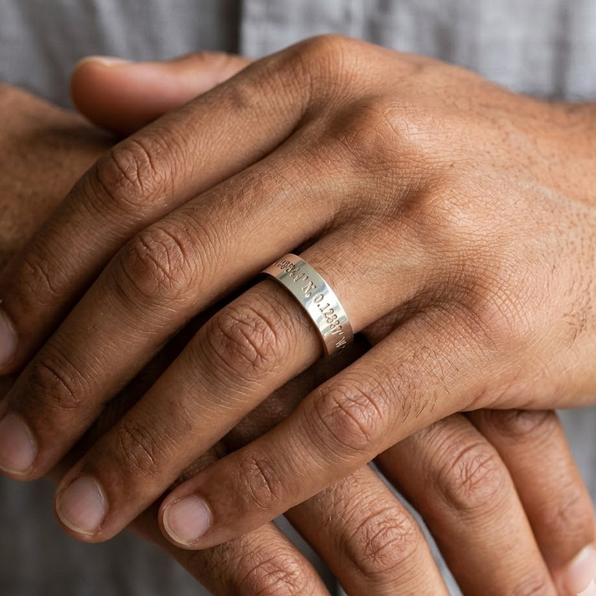 coordinates engraved silver ring on mans hand