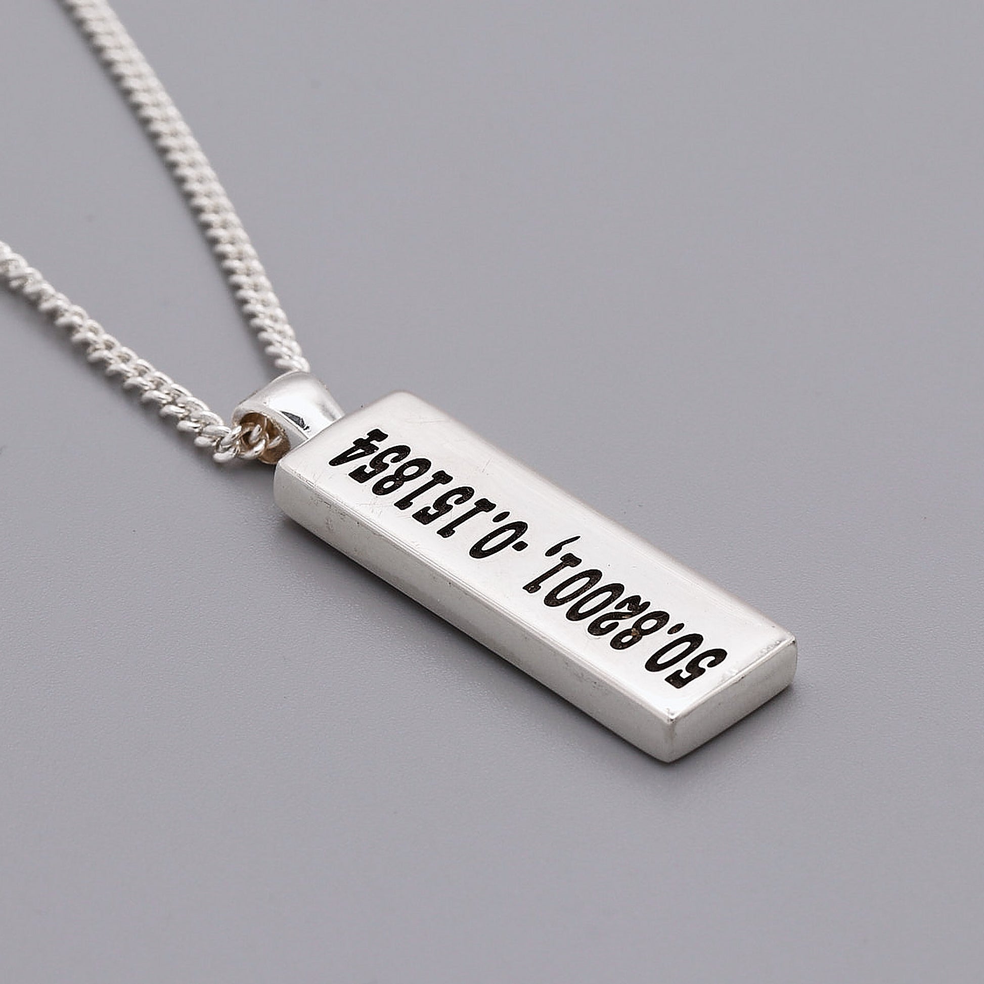 Silver necklace with a rectangular pendant on a gray background