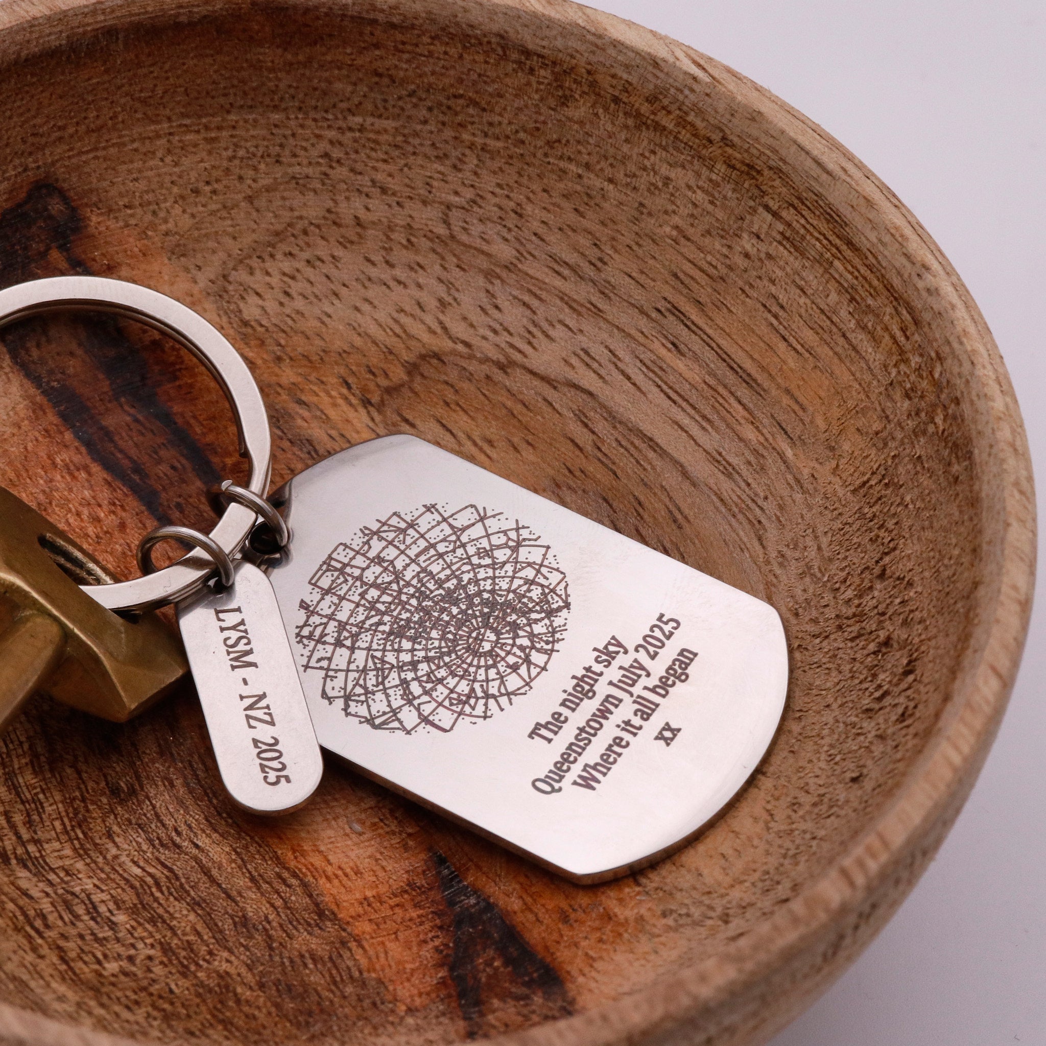 Keyring with engraved star constellation tag on a wooden surface