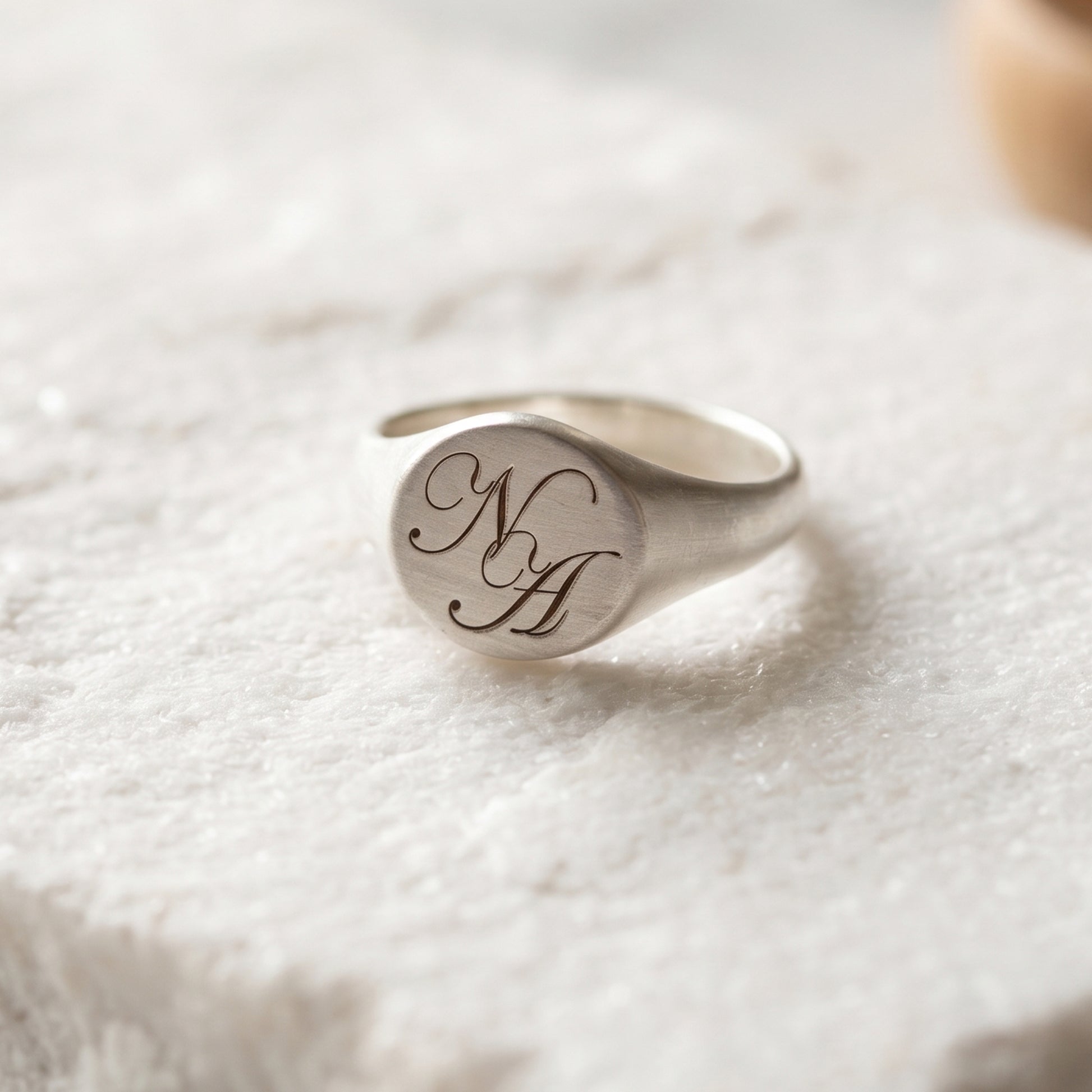 signet ring engraved with N and A initials in a stone surface