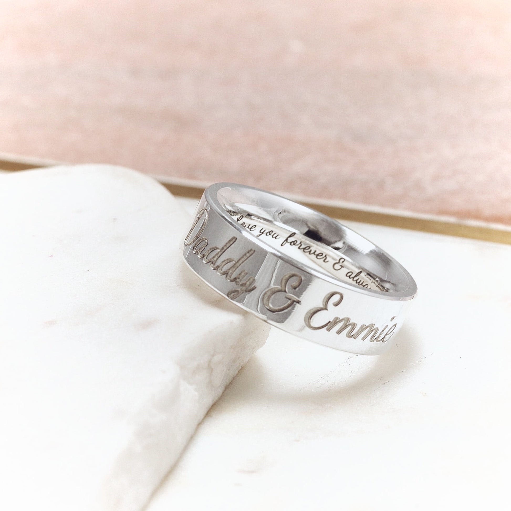 Silver ring with engraved text on a marble surface