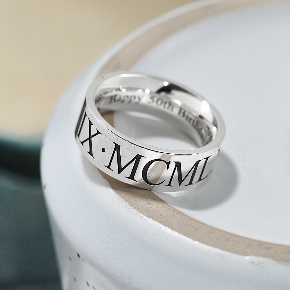 Silver ring with Roman numeral engraving on a white surface