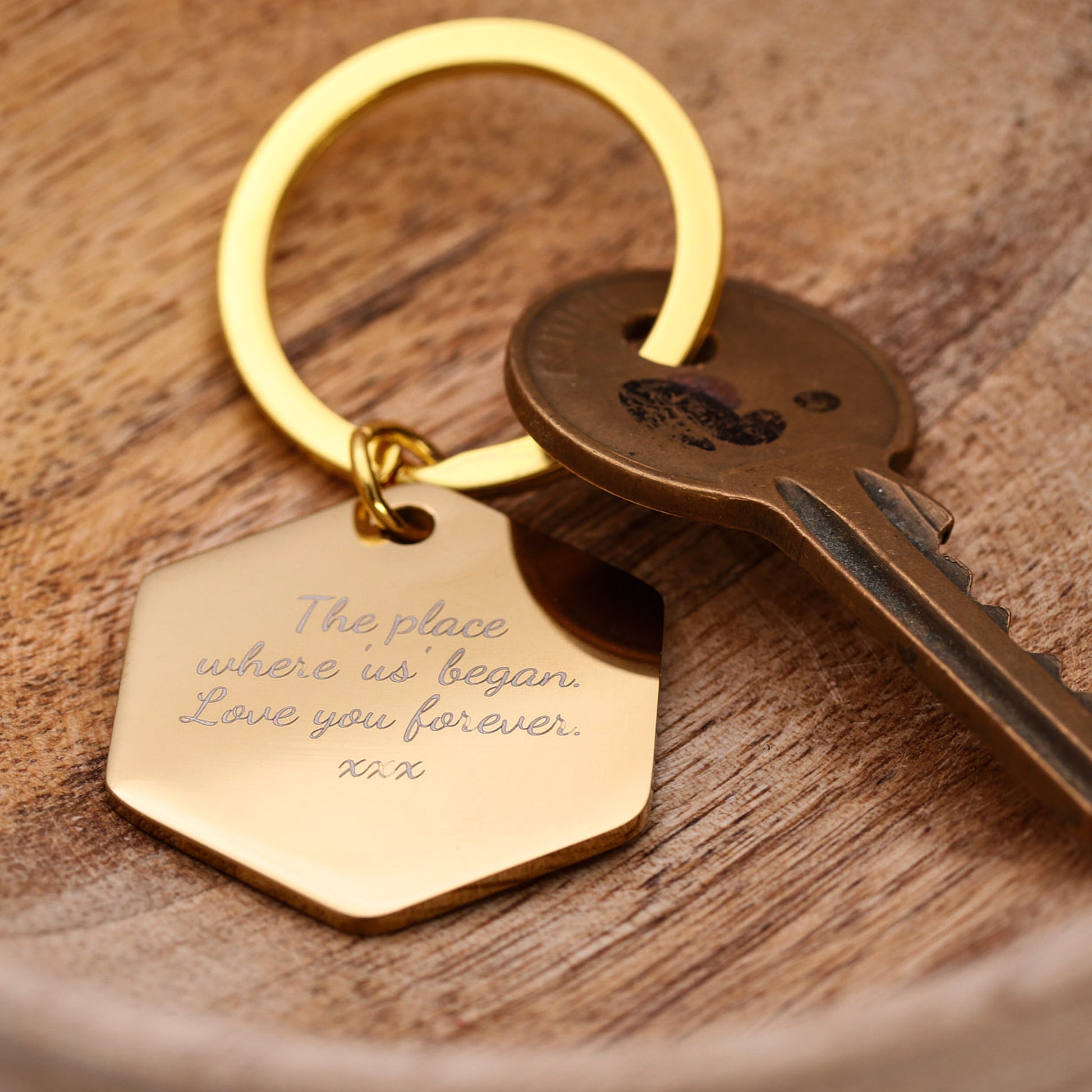 Gold keychain with engraved message on a wooden surface