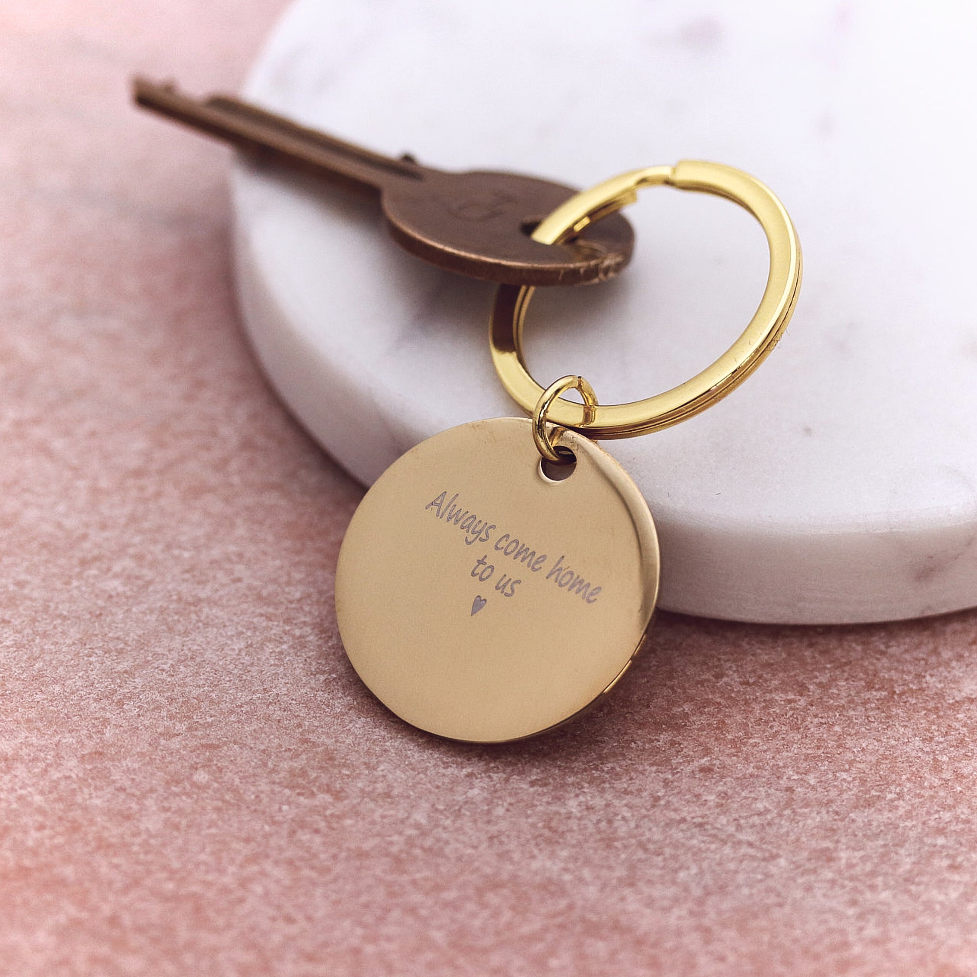 Gold keychain with engraved message on a marble surface