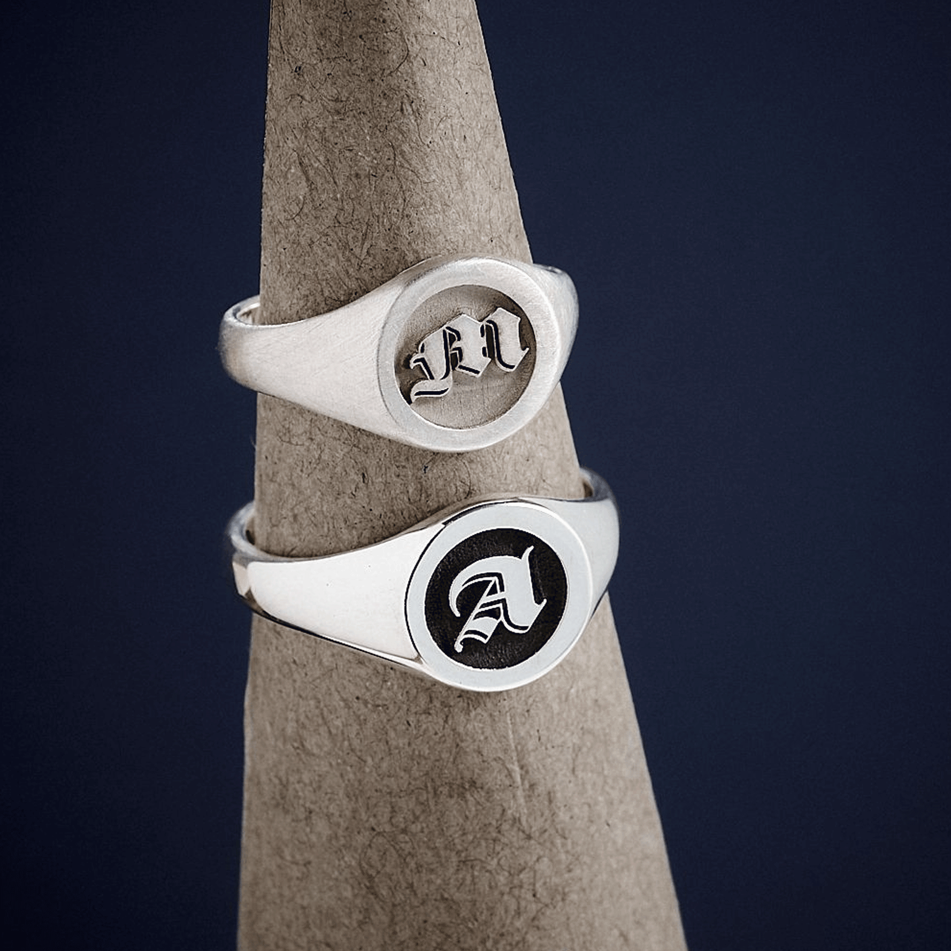Two silver signet rings with engraved initials in gothic font 
