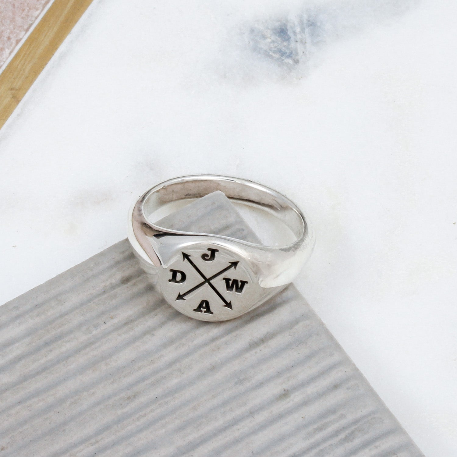 Silver ring with engraved initials on a white surface