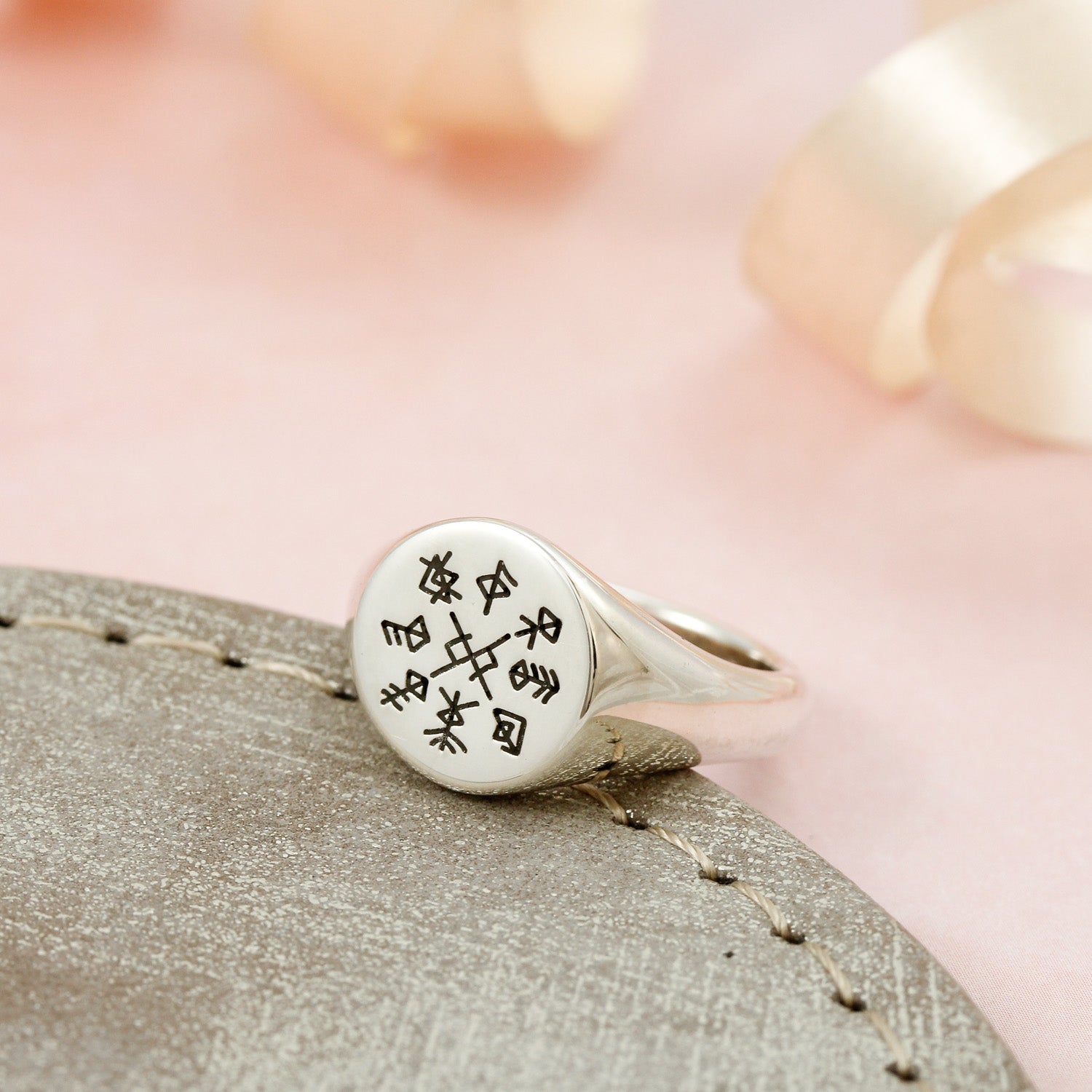 Silver ring with engraved runes design on a textured surface