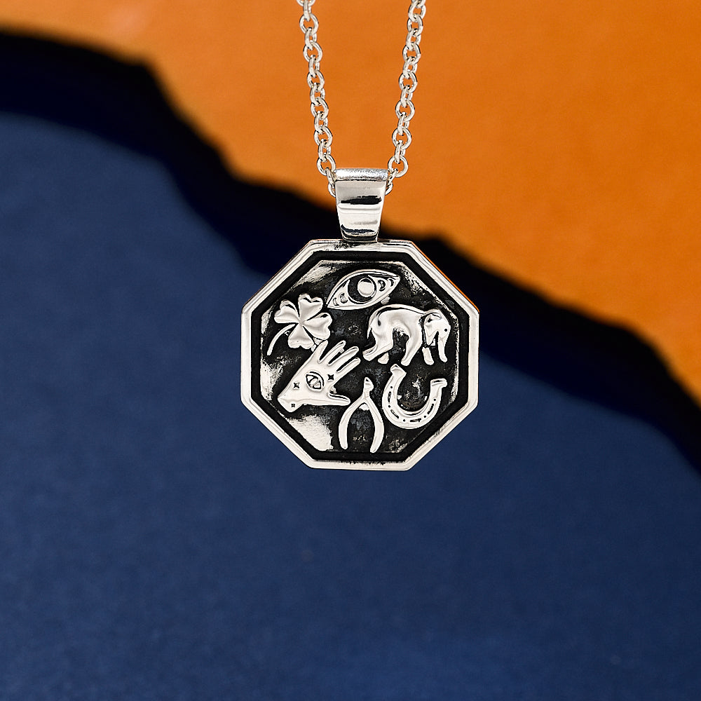 Silver lucky symbols pendant with engravings on a blue and orange gradient background