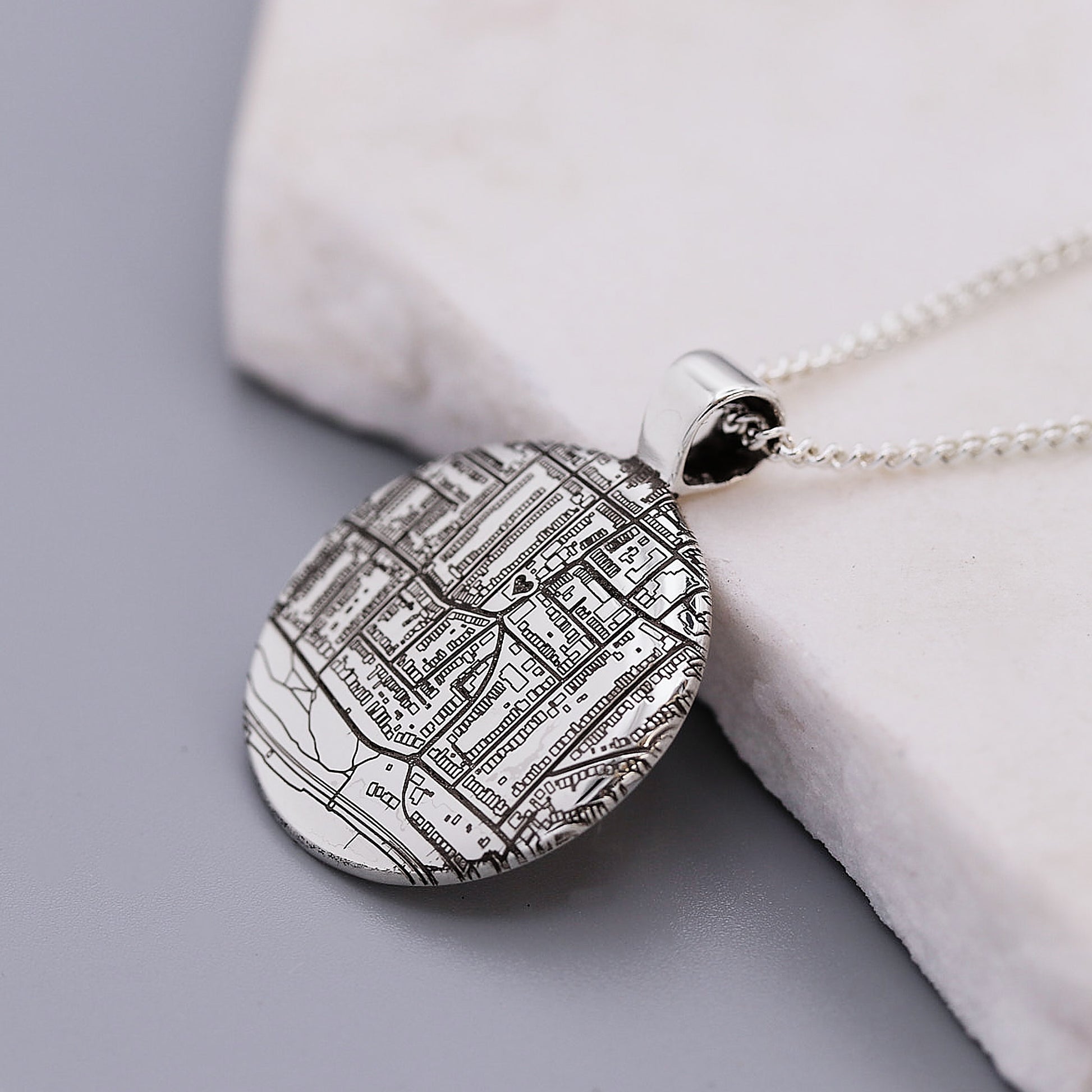 Map pendant necklace on a light gray surface