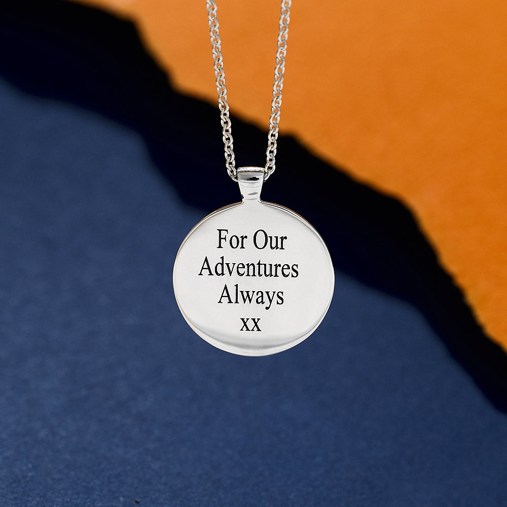 Silver necklace with a round pendant on a blue and orange gradient background