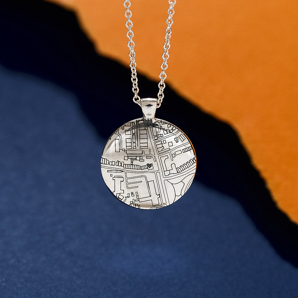 Silver necklace with a circular pendant featuring custom street map design on a blue and orange gradient background
