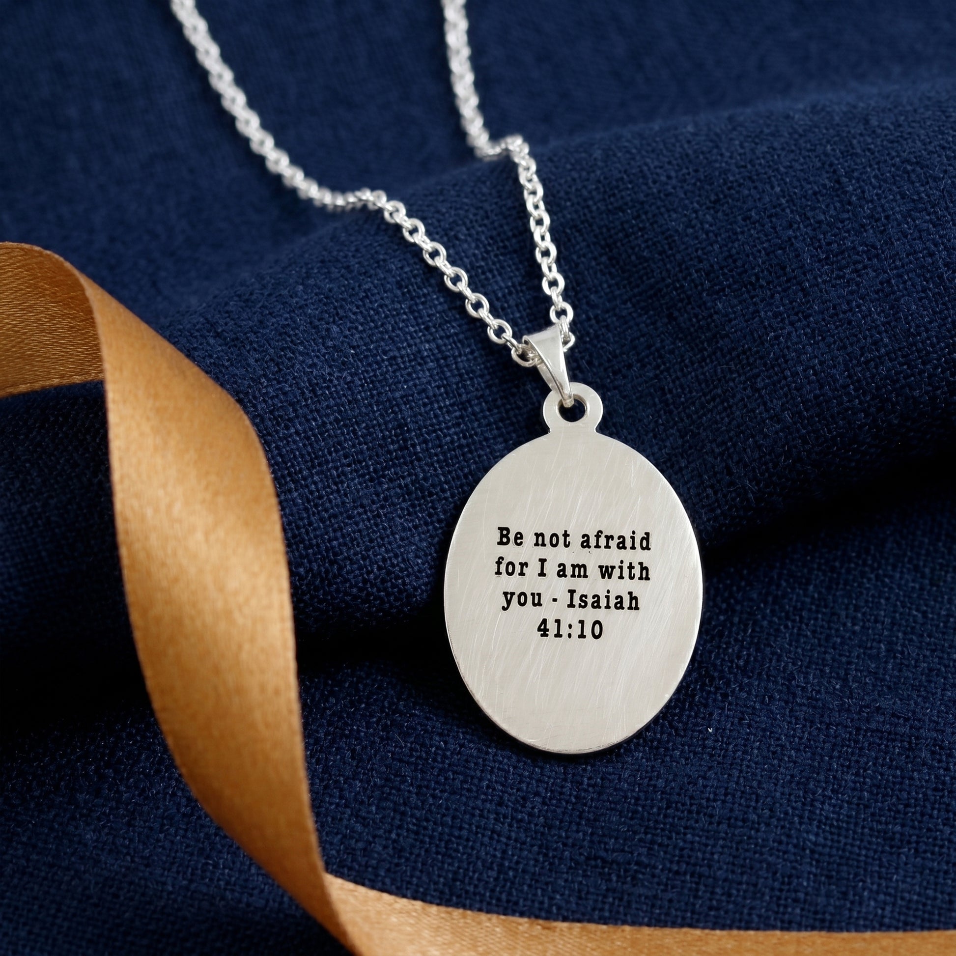 Silver necklace with an engraved pendant on a blue fabric background