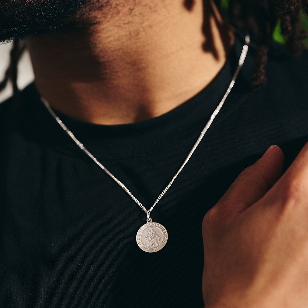 man wearing a saint christopher necklace with curb chain