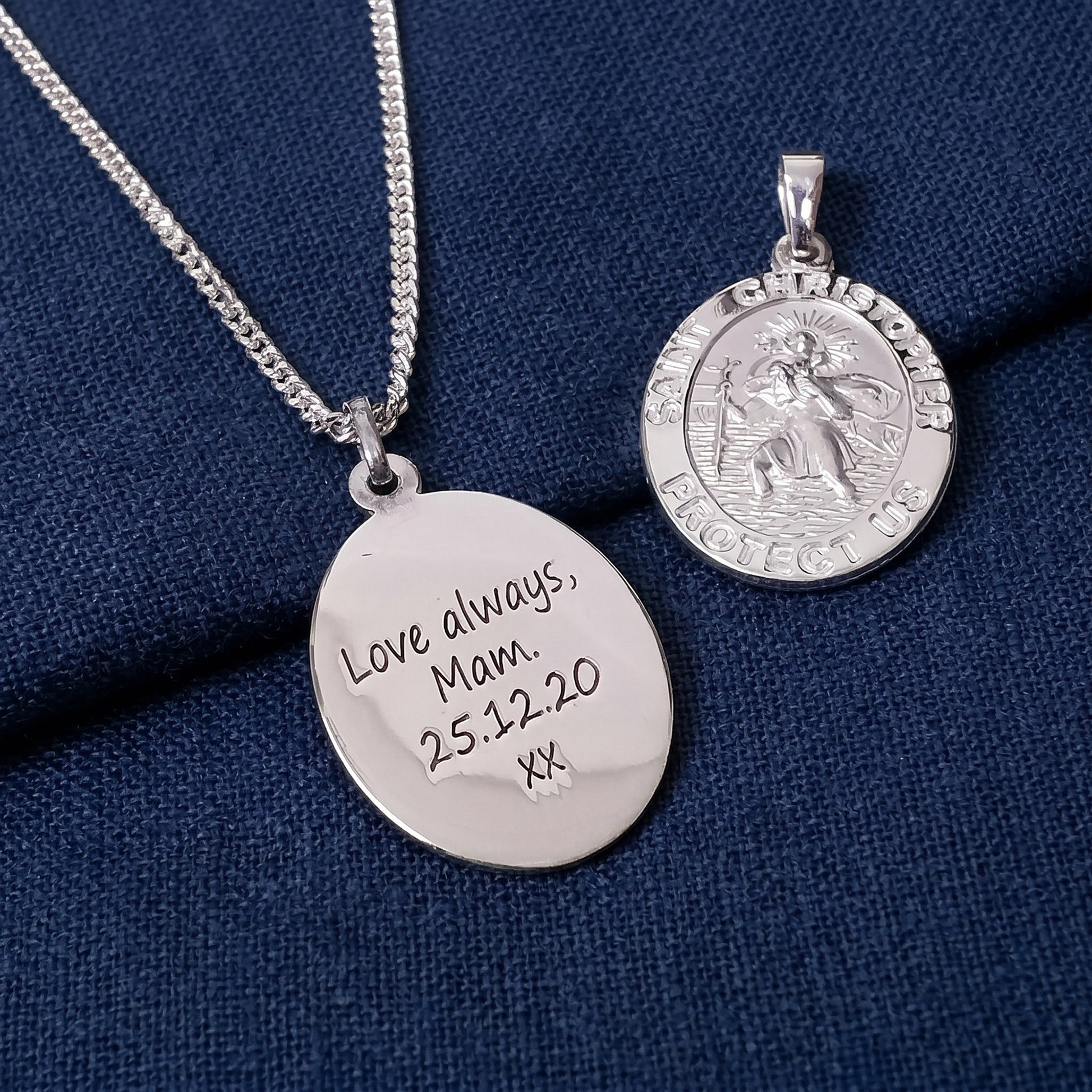 Two silver pendants on a blue fabric background