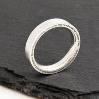Silver ring with engraved text on a dark stone surface