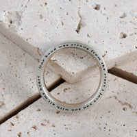 Silver ring with engraved text on a stone surface