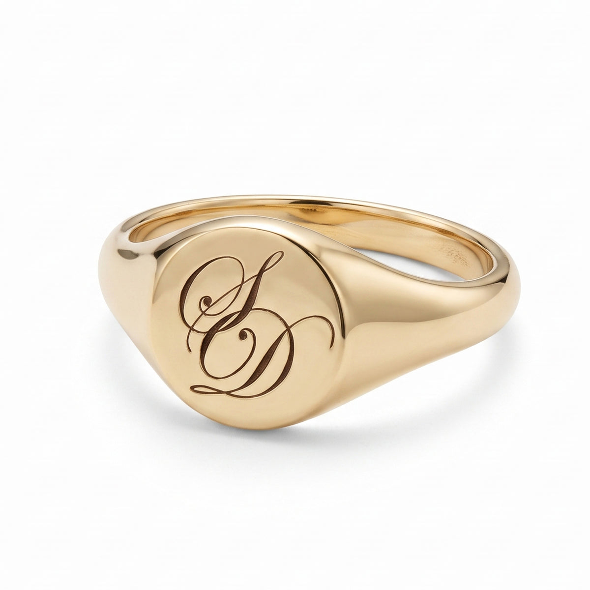 A polished yellow gold signet ring with an engraved cursive monogram on a clean white background.