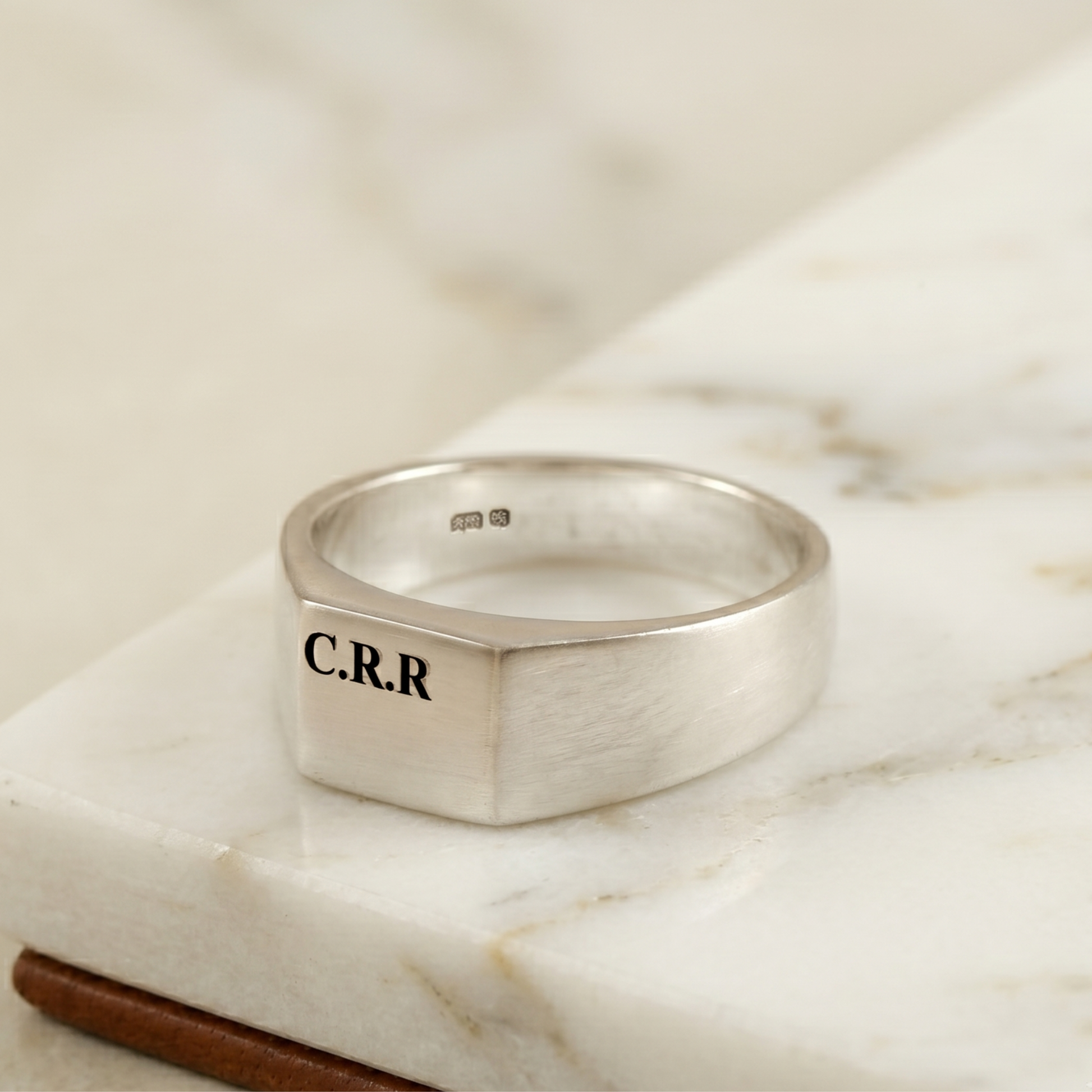 silver ring engraved with CRR on a white surface