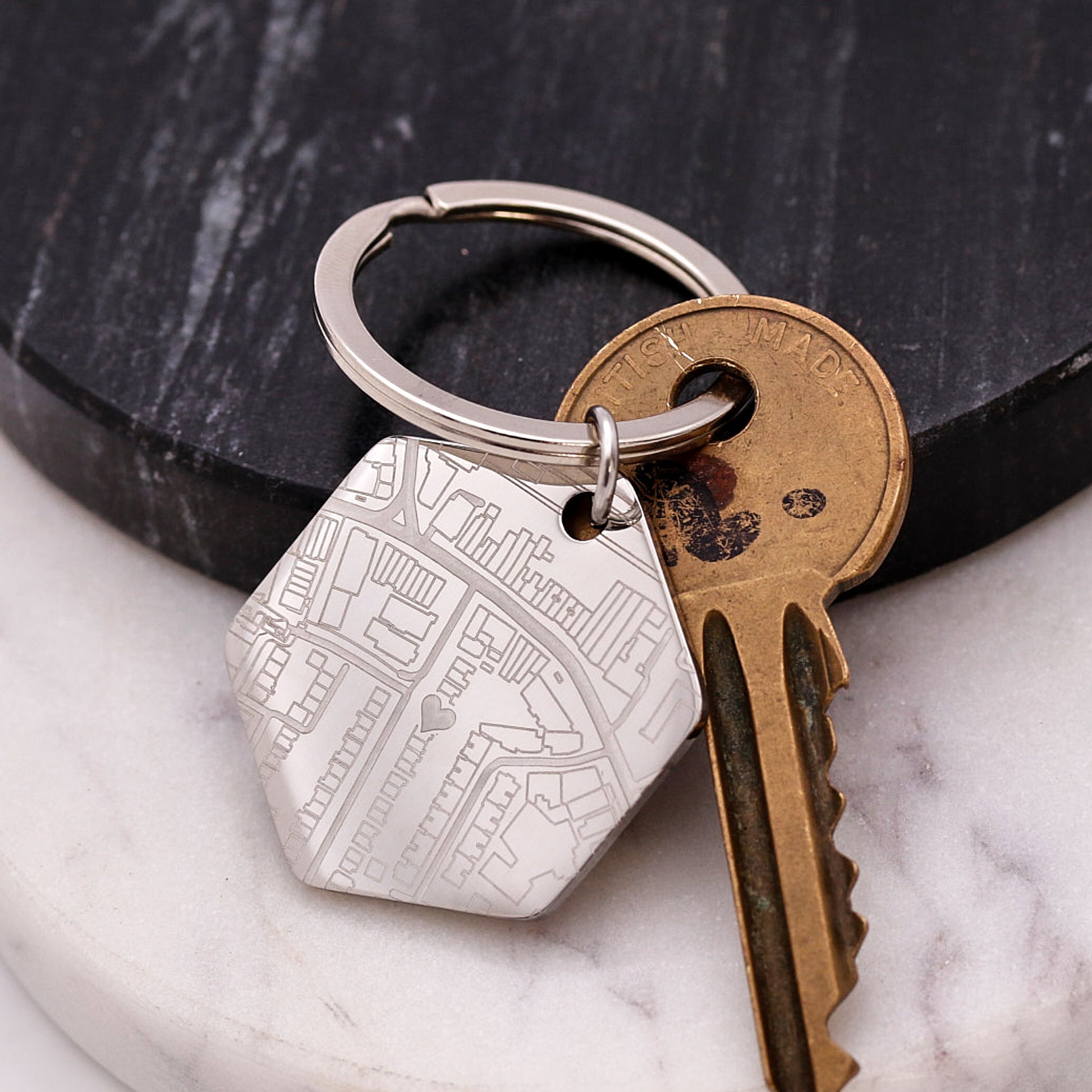 Keychain with a silver tag and a bronze key on a marble surface